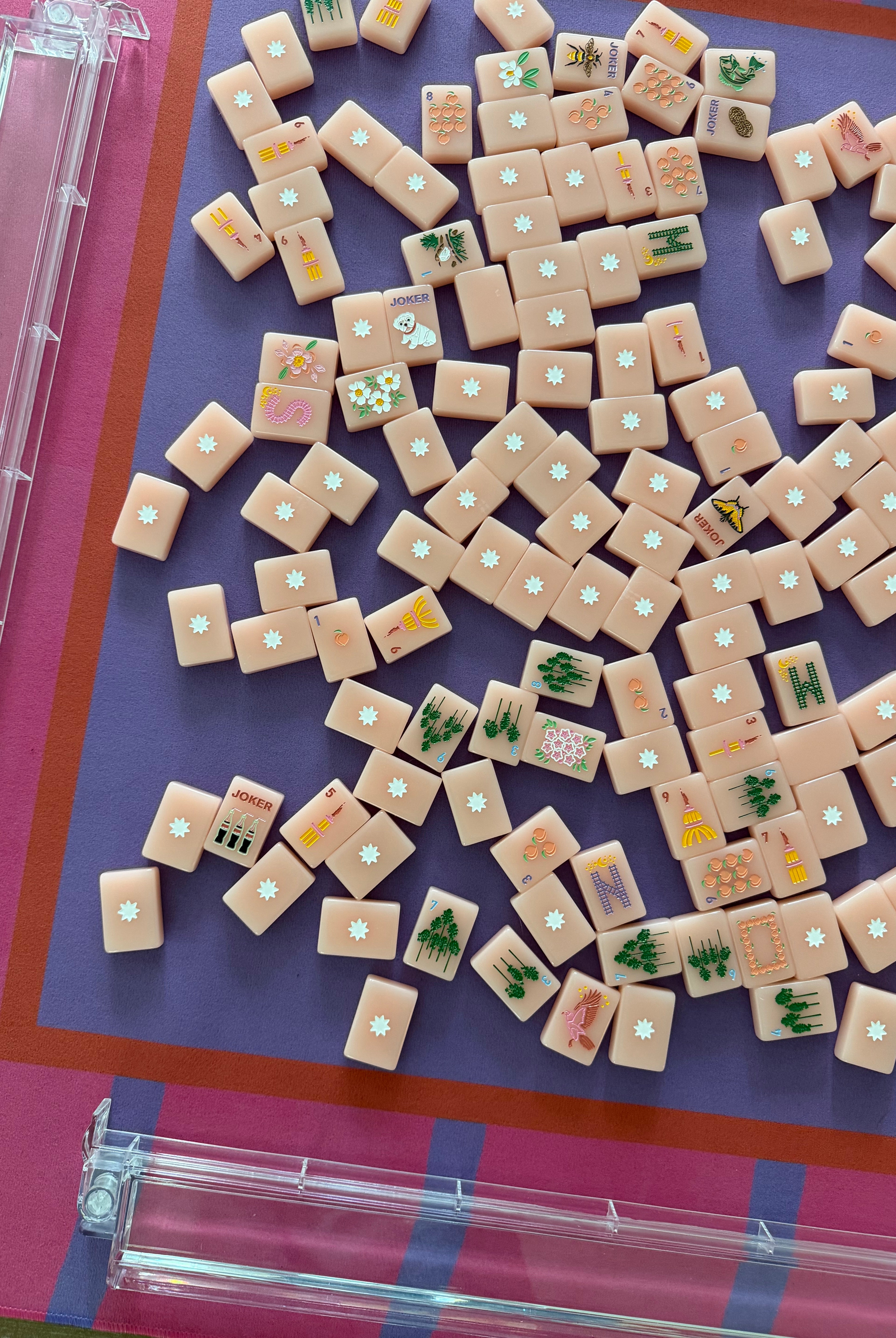 Maximalist hot pink and lavender wavy stripe mahjong mat with peach colored mahjong tiles. Close up of a mahjong table setup