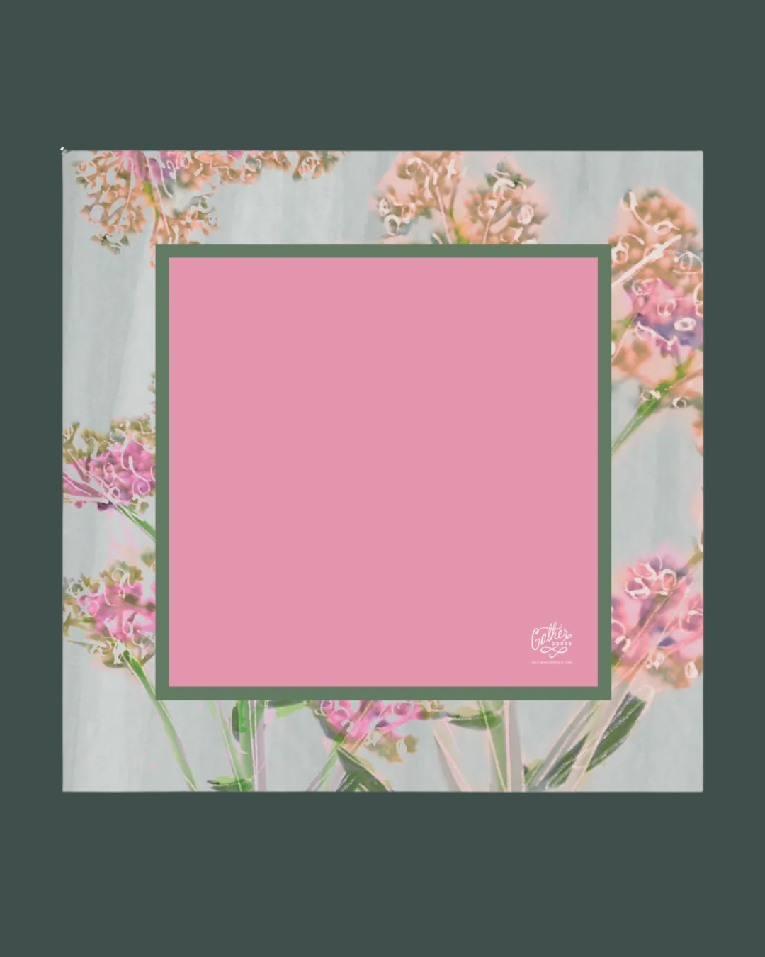 A square pink mahjong mat with a dark green border, centered on a floral background with a dark green outer border. A small white logo is visible in the bottom-right corner of the pink area.