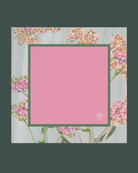 A square pink mahjong mat with a dark green border, centered on a floral background with a dark green outer border. A small white logo is visible in the bottom-right corner of the pink area.